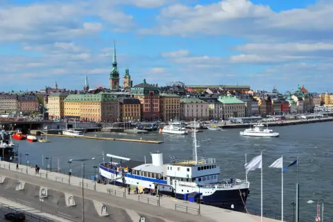 Widok na port w Sztokholmie, gdzie cumuje prom. W tle kolorowe kamienice i wieże.