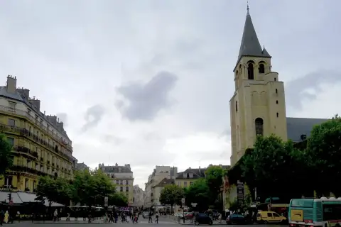 Wieża kościoła Saint-Germain-des-Prés na tle paryskiej ulicy z budynkami i przechodniami.