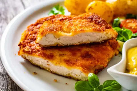 Chrupiący kotlet drobiowy, idealny sposób na to, jak odgrzać smażonego kotleta drobiowego żeby panierka znowu była chrupiąca. Podany z ziemniakami i sosem.
