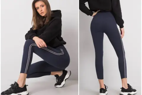 Modelka prezentuje granatowe legginsy z lampasami. Idealne do sportowych stylizacji, świetnie wyglądają z bluzą i sneakersami. Co założyć do legginsów? Taki zestaw to strzał w dziesiątkę!