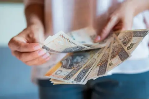 Ręce trzymające polskie banknoty 200 zł. Zastanawiasz się, jak zgłosić spadek w gotówce?