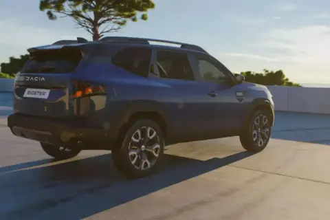 Niebieski Dacia Bigster na tle nieba i drzewa. Zbliżają się jego wymiary.