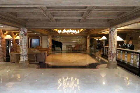 Eleganckie lobby hotelowe z fortepianem, recepcją i dwoma pracownikami.