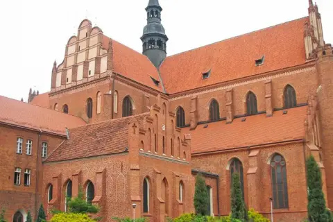 Imponująca ceglana katedra w Pelplinie z charakterystycznymi dachami i wieżą.