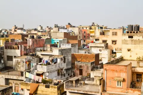 Gęsto zabudowane dachy w New Delhi, świadczące o dużej **new delhi ludność**. Widać pranie rozwieszone do suszenia i zbiorniki na wodę.