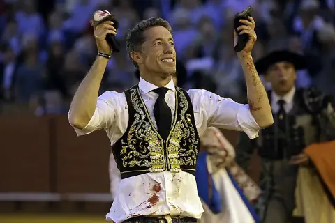 Manuel Escribano, triunfador, levanta las orejas del toro en la plaza.