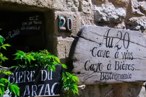 Bonjour! Drewniany szyld "Au 20" zaprasza do piwnicy z winami i piwami. Obok tablica z napisem "Biere du Arzac".