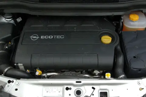 Silnik Ecotec w Oplu Zafira B. Widoczny czarny plastikowy dekiel z logo Opla i napisem Ecotec, żółty korek oleju i zbiorniczek płynu chłodniczego.
