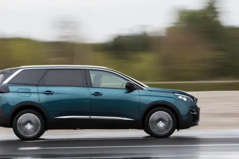 Turkusowy Peugeot 5008 2.0 HDI w ruchu, z rozmytym tłem.