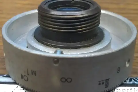 Metalowy pierścień z oznaczeniami od 1 do 8, nieskończoności i innymi symbolami, służący do regulacji obiektywu. Idealny do zoom test.