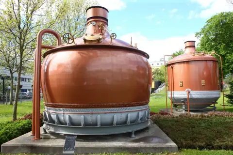 Dwa miedziane kadzie warzelnicze, świadkowie historii piwa specjal, stoją dumnie na trawniku.