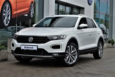 Biały Volkswagen T-Roc, jeden z popularnych volkswagen suv modele, zaparkowany przed salonem.