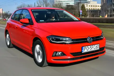 Czerwony Volkswagen Polo 6 w ruchu miejskim. Kierowca w szarej bluzie prowadzi auto.