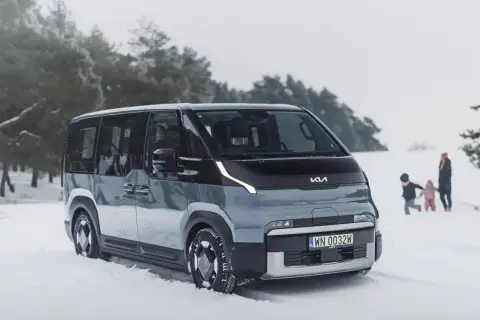 Nowy Kia PV5 w zimowej scenerii. Rodzina bawi się na śniegu w tle.
