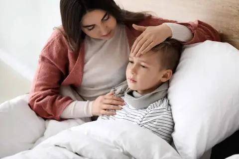 Matka sprawdza gorączkę chorego synka. Opieka na dziecko ile dni trwa, gdy jest chore?