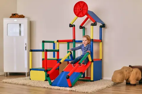 Kleines Kind rutscht auf bunter Spielburg. Tolle quadro aufbau ideen für das Kinderzimmer.