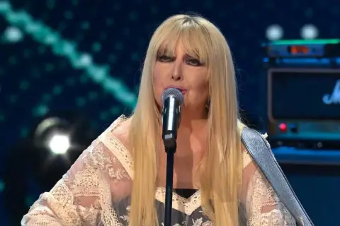 Wokalistka z długimi blond włosami śpiewa przy mikrofonie. W tle widać wzmacniacz Marshall. Idealnie pasuje do jesiennych nastrojów, tworząc piosenki o jesieni dla dorosłych.