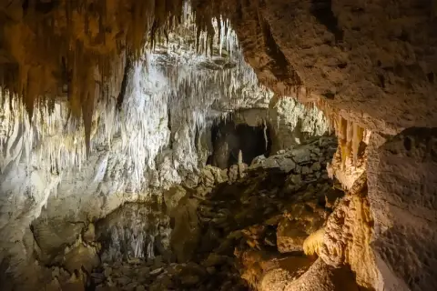 Wnętrze jaskini z naciekami skalnymi i kamienistym dnem.