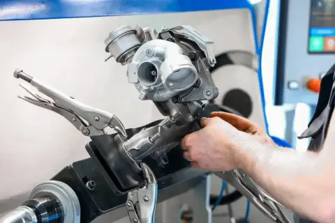 Mechanik pracuje nad turbosprężarką, przygotowując ją do czyszczenia n75. Urządzenie jest zamocowane w imadle.