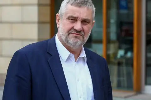 Mężczyzna z siwą brodą w granatowej marynarce i białej koszuli. Czy pozna prawdę o zarzutach prokuratorskich dla byłego ministra rolnictwa w 2025 roku?