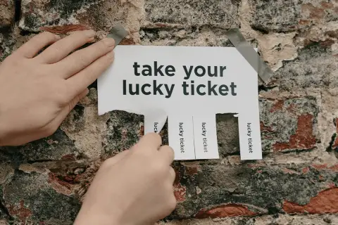 Hands tear off "lucky ticket" strips from a poster on a brick wall, offering great raffle ideas.