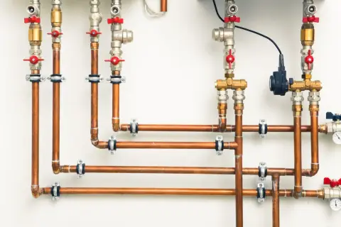 System hydrauliczny z miedzianymi rurami i zaworami. Różnica między złączkami PEX U czy TH jest kluczowa dla szczelności instalacji.