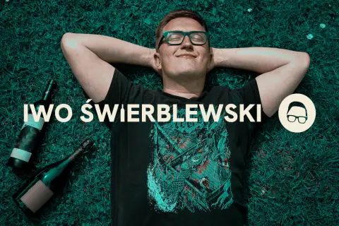 Przyczyny "łez" na ściankach kieliszka mówią o zawartości alkoholu. Mężczyzna leży na trawie obok butelek.