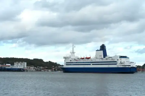 Duży prom pasażerski, podobny do tych kursujących na trasie Dover, zacumowany przy brzegu.