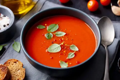 Prosta zupa paprykowa, ozdobiona listkami bazylii i płatkami chili, podana z grzankami.