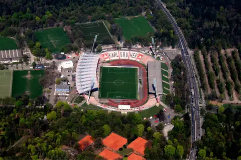 Stadion Karlsruher SC z lotu ptaka, z boiskiem, trybunami i otaczającym go lasem.