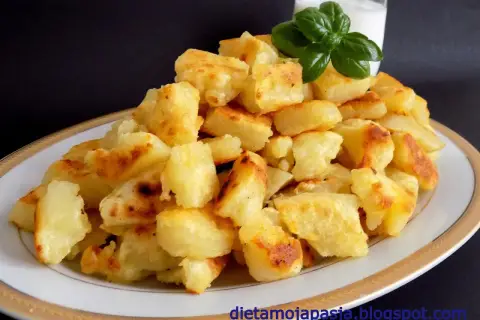 Usmażone ziemniaki na talerzu, obok szklanka mleka i listek bazylii.
