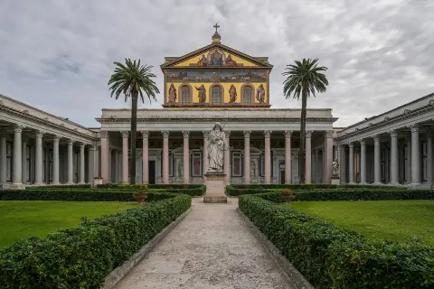 Il cortile della cattedrale San Paolo a Roma, con statue e palme, invita alla contemplazione.