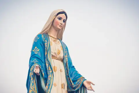 Posąg Matki Boskiej w niebieskim płaszczu ze złotymi zdobieniami, jakby witała rycerzy Maryi.