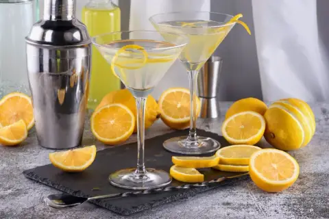 Dwa kieliszki z martini, cytryny i shaker. Idealne na orzeźwiający drink.
