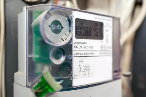 Cyfrowy licznik energii elektrycznej z widocznym wyświetlaczem i schematem podłączenia.