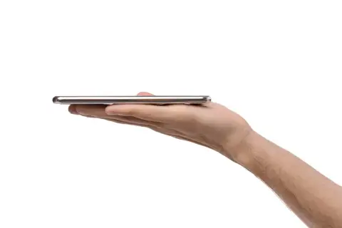 Dłoń trzyma cienki, srebrny smartfon. Może to być nowy model, np. kierunkowy 95 Polska.