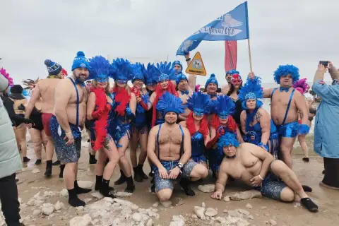 Grupa morsów w niebieskich piórach i maskach pozuje na plaży. Pewnie zastanawiają się, ile stopni ma Bałtyk w styczniu.