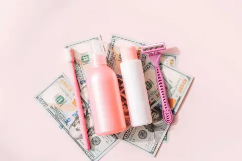 Rosa Rasierer, Zahnbürste und Kosmetikflaschen auf 100-Dollar-Scheinen. Ein Symbol für den "Pink Tax", der Frauen mehr kostet.