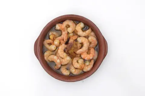 Gambas al pil pil burbujeantes en cazuela de barro, con ajo y aceite de oliva.