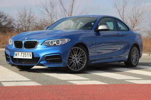 Niebieskie BMW 235i na pasach. Sportowy samochód z charakterystycznym grillem i felgami.