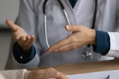Lekarz omawia z pacjentem objawy, w tym uporczywy kaszel, który może być symptomem raka płuc.