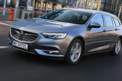 Szary Opel Insignia 2.0 CDTI w wersji kombi jedzie po miejskiej drodze.