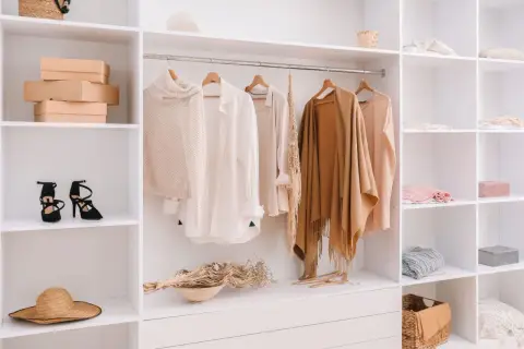 Armario organizado con ropa de punto, camisas y chales en tonos neutros, perfecto para tu colección de otoño.