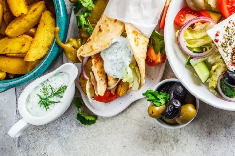 Pyszne greckie danie: gyros w picie, frytki, sałatka grecka z fetą i oliwkami, sos tzatziki.