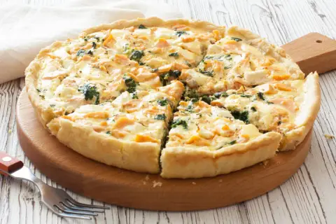 Pyszna tarta z łososiem, szpinakiem i serem feta, pokrojona na kawałki, gotowa do podania.