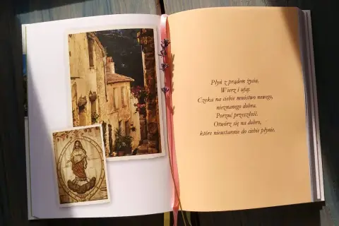 Otwarta książka z obrazkami włoskiej uliczki i postacią Matki Boskiej, obok tekst modlitwy.