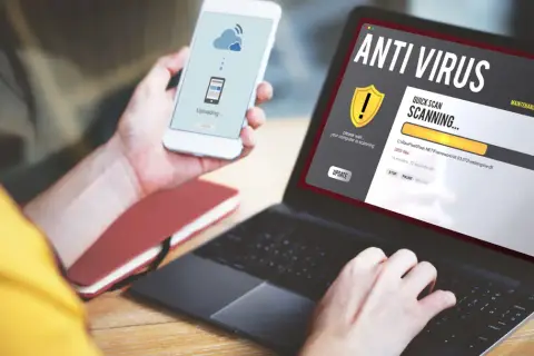 Osoba korzysta z laptopa z programem antywirus free, który skanuje komputer. Na telefonie widnieje komunikat o przesyłaniu danych.