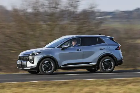 Srebrny SUV Kia Sportage, jeden z najnowszych modeli, jedzie po drodze.