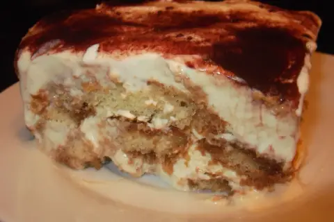 Pyszny kawałek tiramisu bez alkoholu, z warstwami biszkoptów i kremu, posypany kakao.