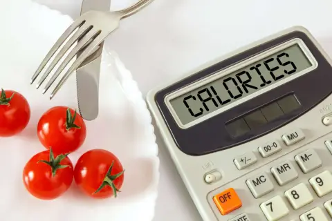 Pomidorki i kalkulator z napisem "CALORIES". Czy na keto trzeba liczyć kalorie? To pytanie zadaje sobie wiele osób.